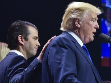 Donald Trump, Jr., (L) places a hand on the shoulder of his father, Republican presidential nominee Donald Trump, during in a rally on the final night of the 2016 US presidential election at the SNHU Arena in Manchester, New Hampshire on November 7, 2016. / AFP / MANDEL NGAN (Photo …