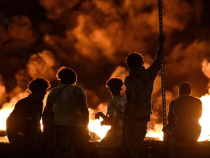 TOPSHOT - People look at burning tyres blocking a street in Bordeaux,, south-western France on late June 29, 2023, during riots and incidents nationwide after the killing of a 17-year-old boy by a police officer's gunshot following a refusal to comply in a western suburb of Paris. (Photo by Philippe …