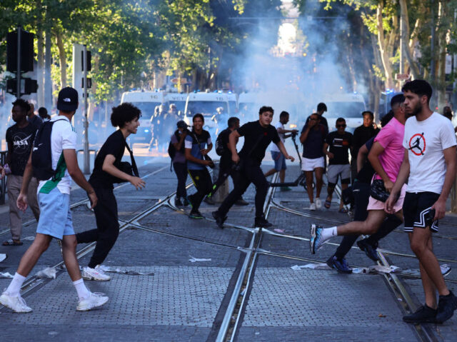 TOPSHOT - Protesters run from launched tear gas canisters during clashes with police in Marseille, southern France on July 1, 2023, after a fourth consecutive night of rioting in France over the killing of a teenager by police. French police arrested 1311 people nationwide during a fourth consecutive night of …