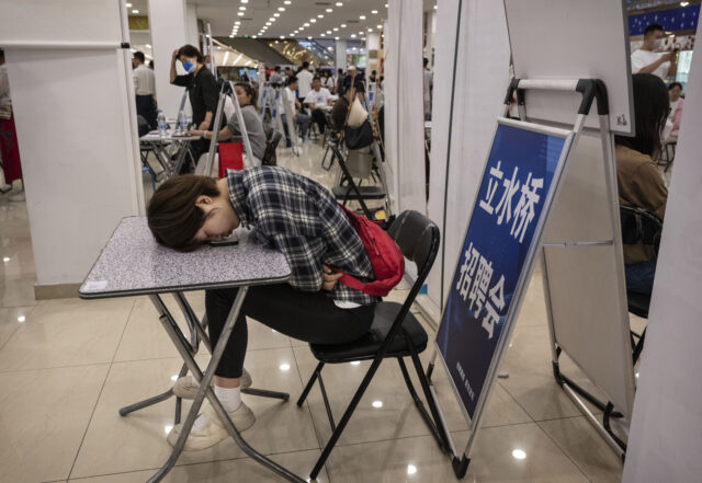 BEIJING, CHINA - JUNE 9: A woman rests on a table at a job fair on June 9, 2023 in Beijing, China. While China’s overall jobless rate is down, youth unemployment in the country is hovering near a record high of 20.4% as the world’s second largest economy slowly emerges …