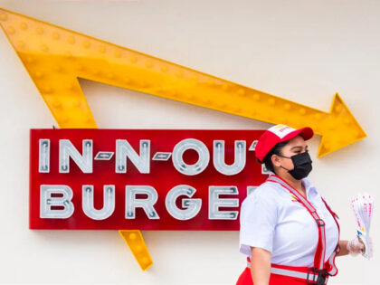 SANTA ANA, CA - APRIL 01: A In-N-Out Burger employee walks past the signage and the new In-NB-Out on North Bristol Street in Santa Ana on Thursday, April 1, 2021. The restaurant opened after the original building was demolished in 2020 to make way for the new building which now …