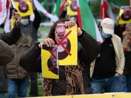 21 September 2021, Berlin: A woman tears up a picture of Iranian President Ebrahim Raisi at a protest event of the National Council of Resistance of Iran (NWRI) in Germany at the Federal Chancellery. With the event, the NWRI is protesting Raisi's speech at the upcoming UN General Debate in …