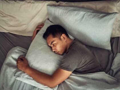 Shot of a young man lying in bed and looking unhappy at home - stock photo