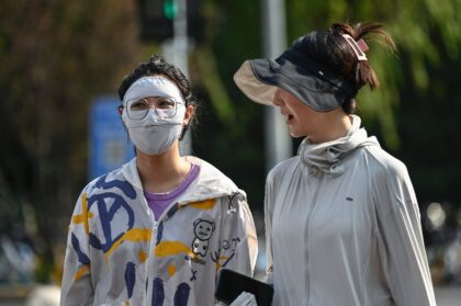 People in the Beijing wear protective clothing as the Chinese capital bakes under a record-breaking run of high temperatures
