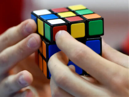 FILE - A gamer plays with Rubik's Magic Cube at the international game fair 'SPIEL' in Essen, Germany, on Oct. 26, 2017. (AP Photo/Martin Meissner, File)